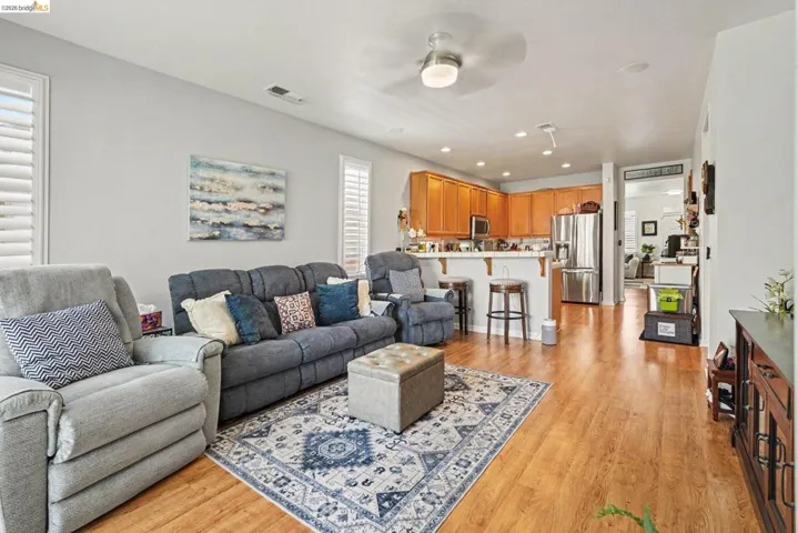 Open-concept living space featuring wood-finish flooring, a ceiling fan with light, and light gray walls
