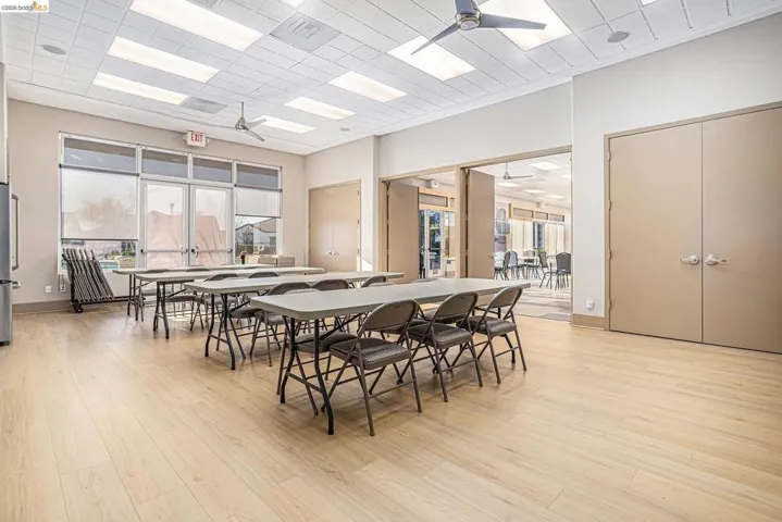 Spacious communal room featuring wood-finish flooring and a drop ceiling with recessed lighting