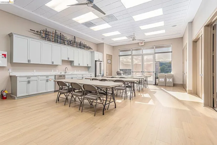 Bright, open common area featuring extensive cabinetry with dark hardware, a stainless steel sink, and built-in appliances
