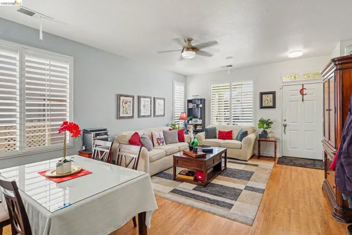 Open-concept living space featuring wood-finish flooring, plantation shutters, and a ceiling fan