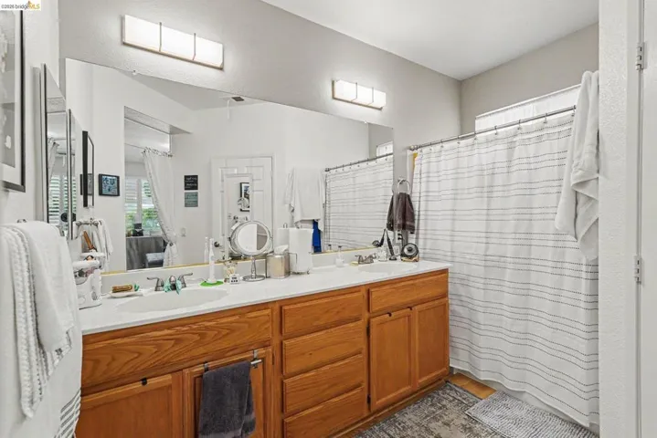 Double vanity with wood-finish cabinetry, white countertops, and integrated sinks