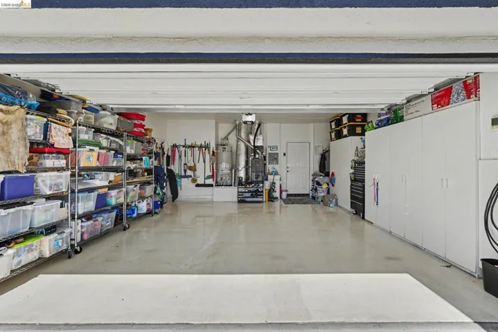 Spacious garage with light gray coated concrete flooring, cabinets, and EV charge outlet.