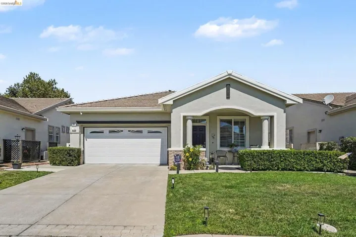 Stucco exterior with a covered entry, stone veneer accents, and a two-car garage