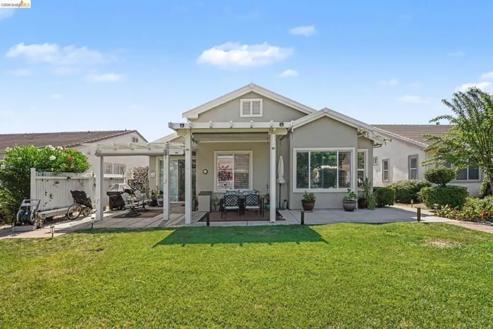 Spacious backyard featuring a manicured lawn, an extended concrete patio, and a dedicated pergola-covered outdoor dining area