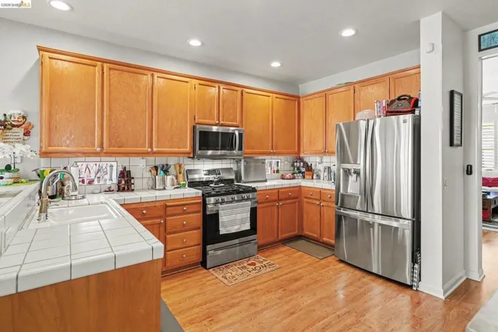 Kitchen with wood-finish flooring, recessed lighting, and a suite of stainless steel appliances