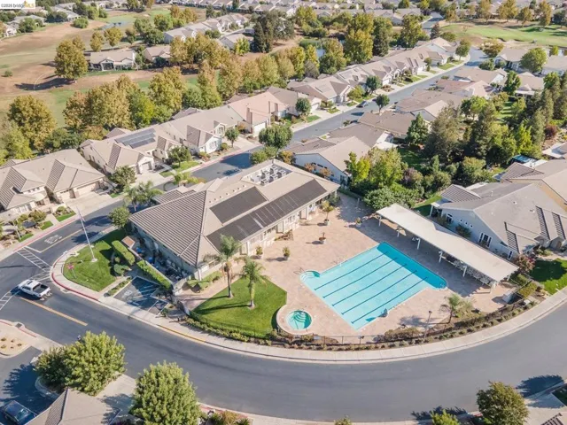 Community recreation area featuring a large swimming pool, circular spa, and ample paved sundeck