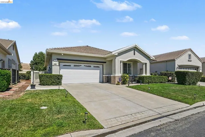 Stucco exterior with a tile roof, featuring an attached two-car garage and a paved driveway