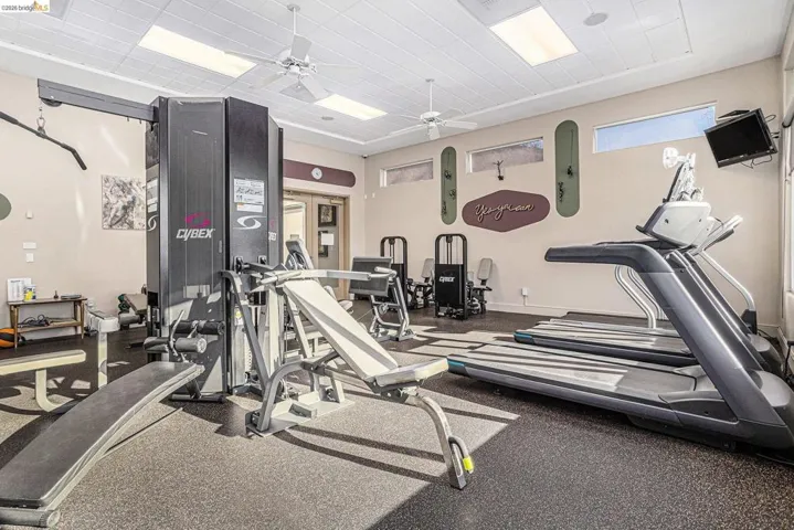 Dedicated fitness space featuring rubberized flooring, ceiling-mounted fans, and recessed lighting