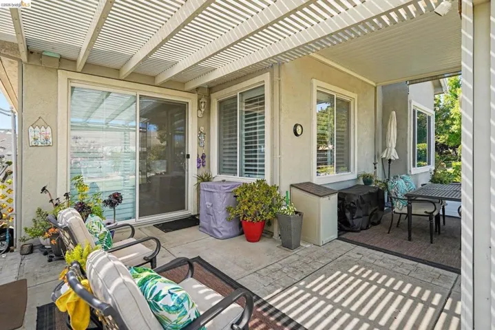 Covered patio featuring a slatted pergola roof and concrete flooring