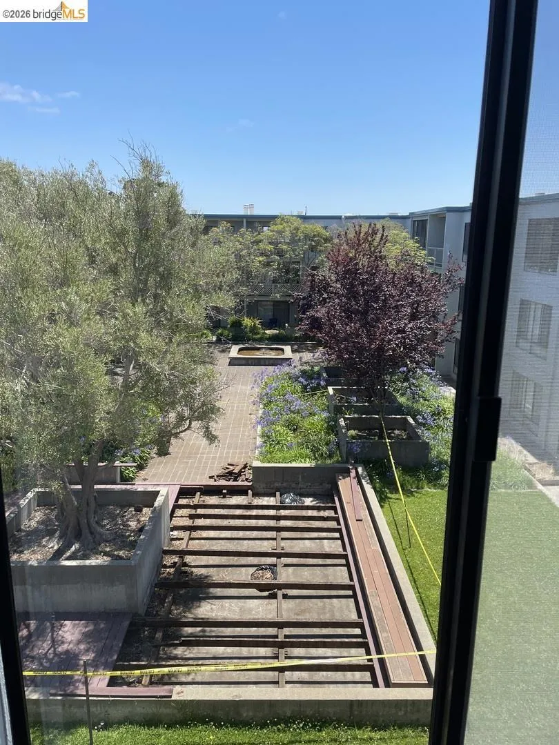 Outdoor courtyard featuring a brick pathway, mature trees, and established plantings