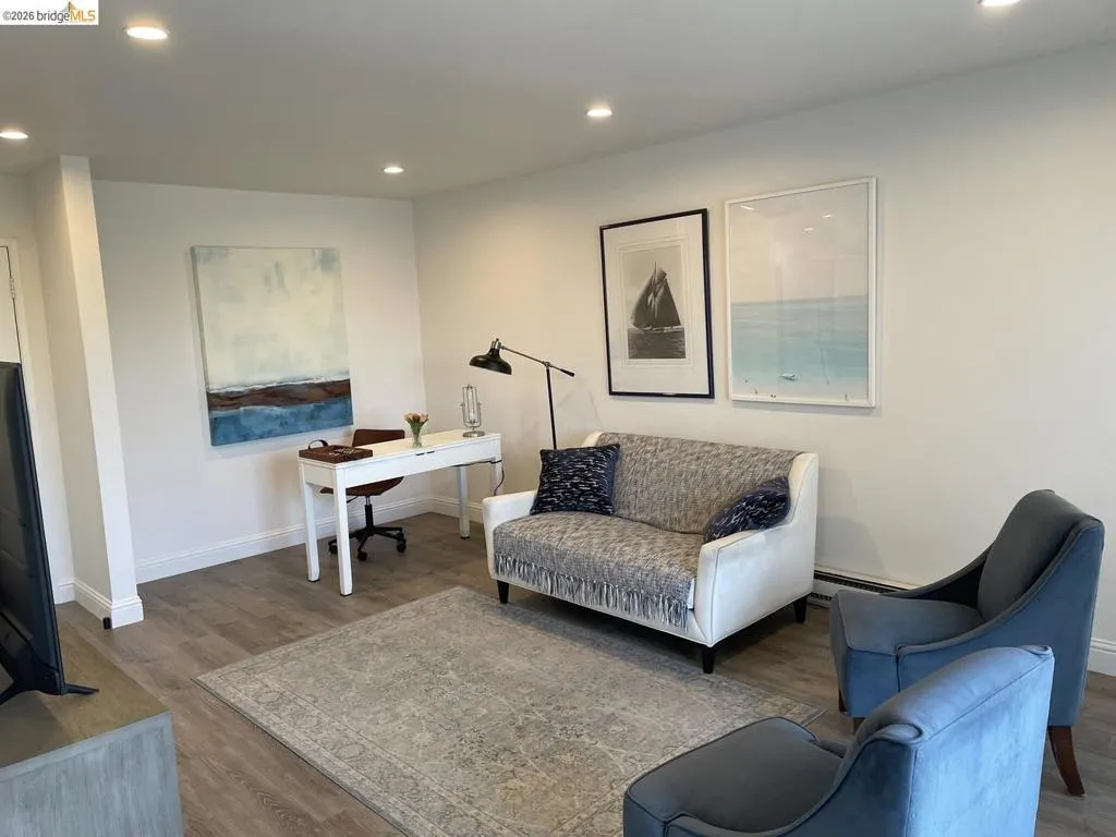 Open living space featuring wood-finish flooring and recessed ceiling lighting