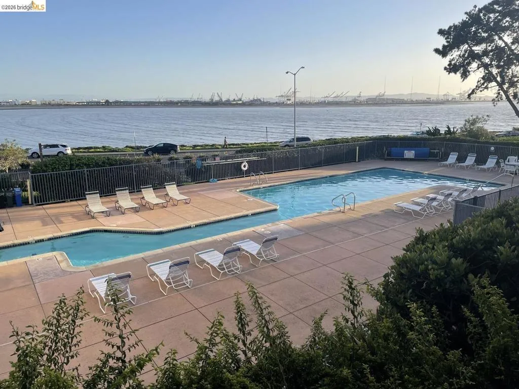 Swimming pool area featuring a perimeter fence, surrounding hardscaping, and a distinct water body with a defined edge