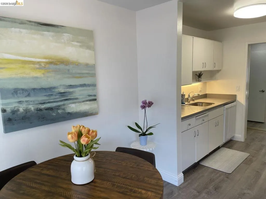 Compact kitchen featuring white cabinetry, light countertops, and a stainless steel sink