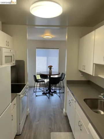 Galley kitchen featuring white cabinetry, gray countertops, and wood-finish flooring