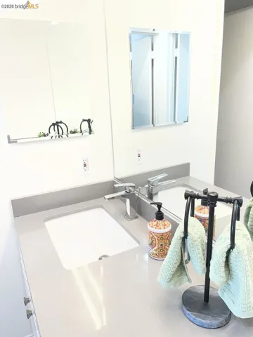 Double vanity featuring integrated sinks, light gray countertops, and polished chrome single-handle faucets