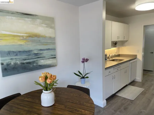 Compact kitchen featuring white cabinetry, light countertops, and a stainless steel sink