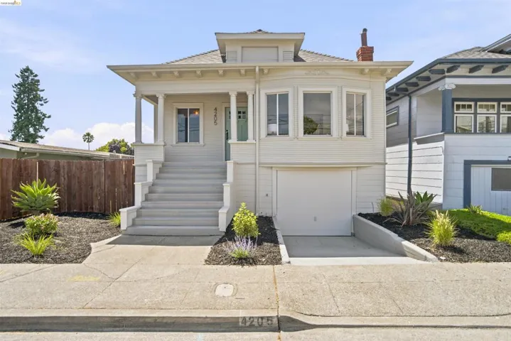 White exterior with a covered porch, column supports, and an integrated garage