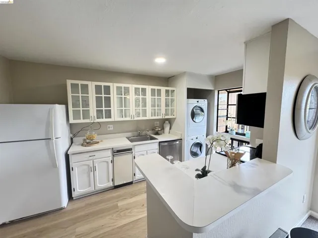 Kitchen featuring white cabinetry with glass-front upper doors, white countertops, and wood-finish flooring