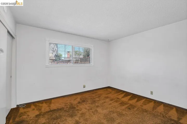Interior room featuring a white ceiling and walls with brown patterned carpeting