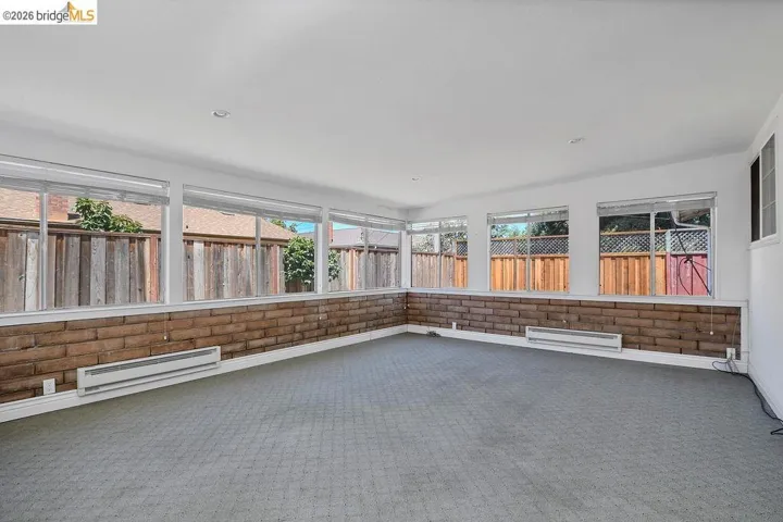 Spacious room featuring extensive window framing, a decorative brick wainscoting, light-colored carpeting, and recessed lighting