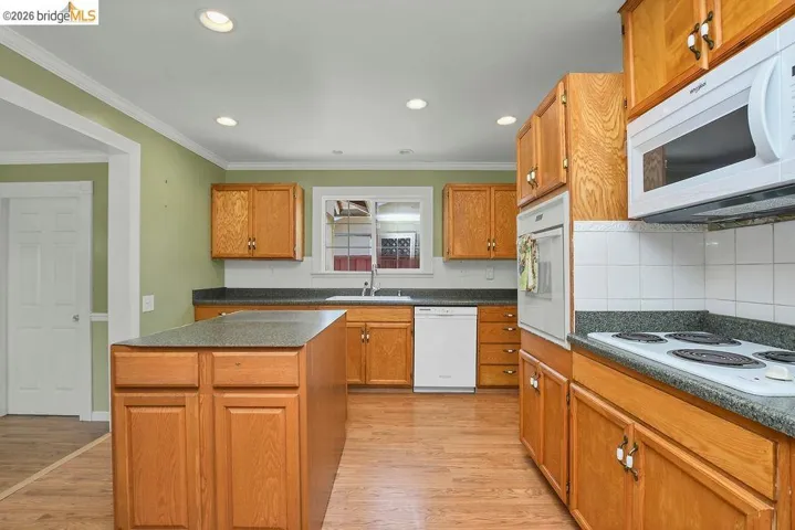 Kitchen featuring wood-finish cabinetry, a central island, recessed lighting, and built-in appliances