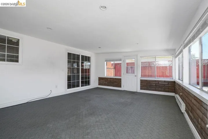 Spacious room featuring broad windows with horizontal blinds, brick wainscoting, and recessed lighting