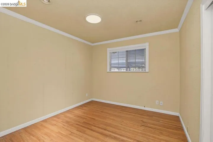 Room featuring wood-finish flooring, a window with blinds, recessed lighting, crown molding, and baseboards