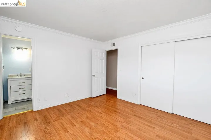 Light-filled room featuring wood-finish flooring, white walls, and crown molding