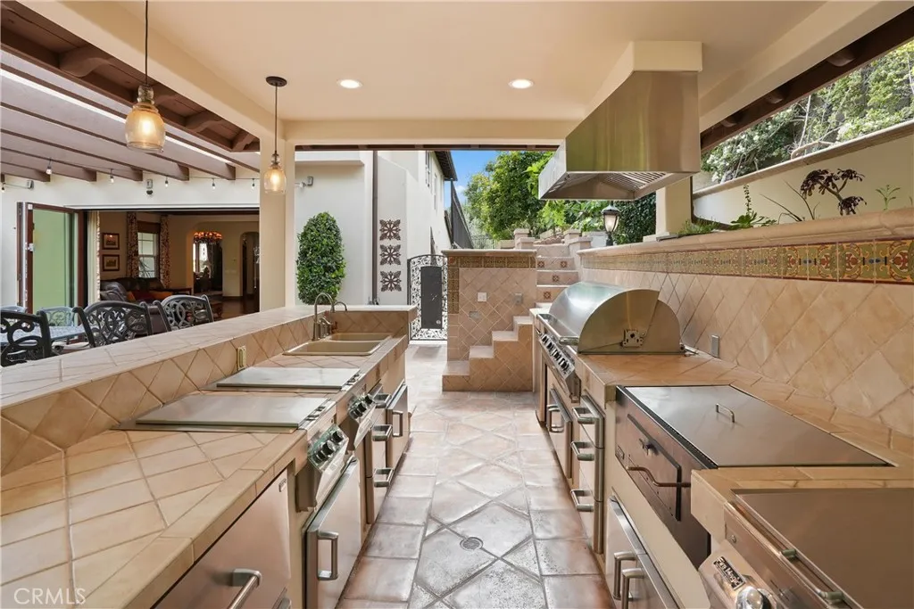 Well-appointed outdoor kitchen designed for effortless entertaining with a built-in BBQ, refrigerator, and bar seating.