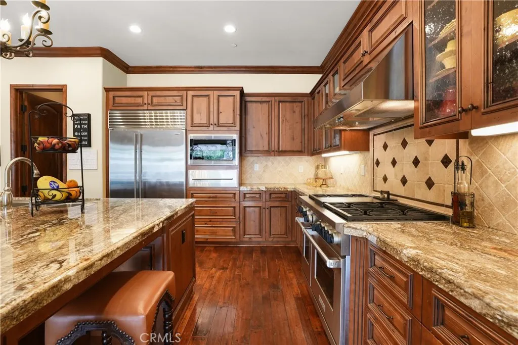 Gourmet kitchen featuring premium Sub-Zero refrigeration, Wolf range, expansive granite center island with seating, and a generous walk-in pantry.