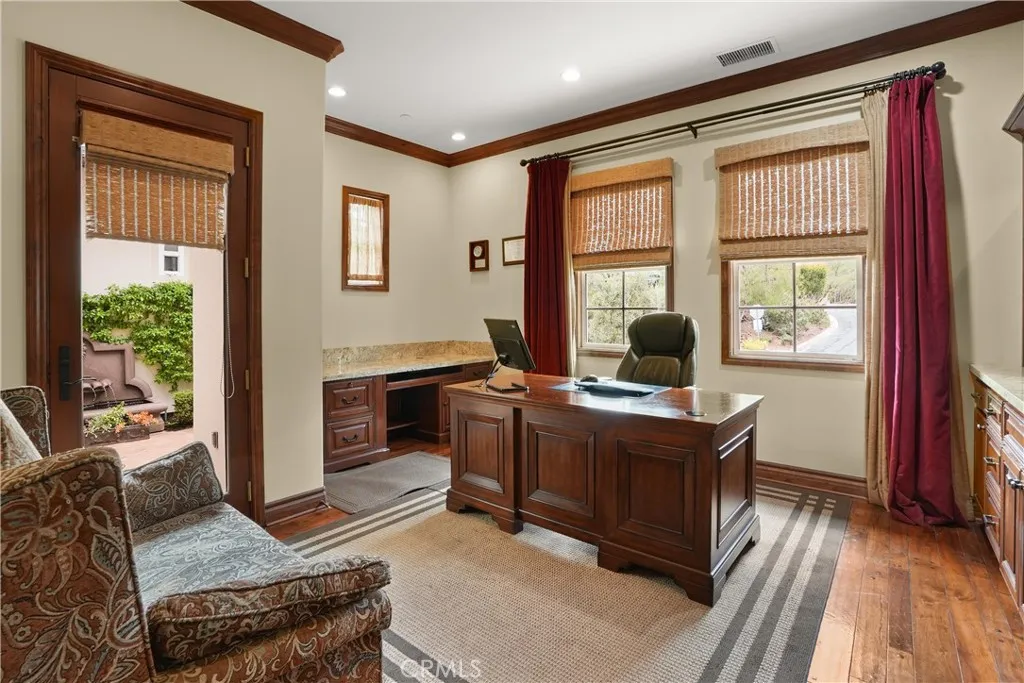 Dedicated office offering custom built-in cabinetry, generous workspace, and seamless access to the gated courtyard.