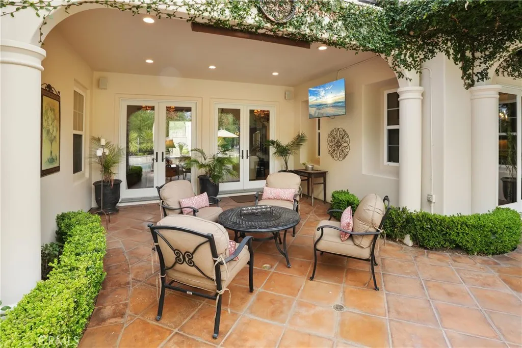 Covered outdoor living area designed for year-round enjoyment, featuring a built-in TV and comfortable seating.