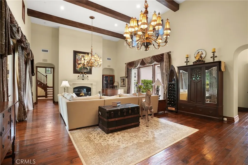 Dramatic great room with soaring ceilings, exposed wood beams, rich hardwood flooring, and elegant architectural details.