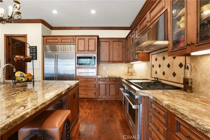 Gourmet kitchen featuring premium Sub-Zero refrigeration, Wolf range, expansive granite center island with seating, and a generous walk-in pantry.