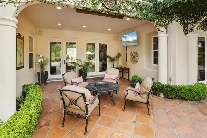 Covered outdoor living area designed for year-round enjoyment, featuring a built-in TV and comfortable seating.