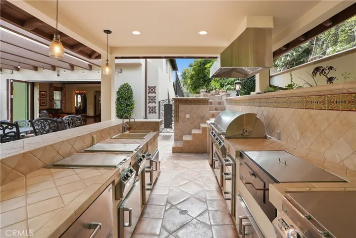 Well-appointed outdoor kitchen designed for effortless entertaining with a built-in BBQ, refrigerator, and bar seating.