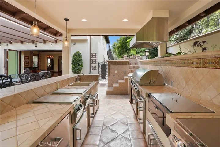 Well-appointed outdoor kitchen designed for effortless entertaining with a built-in BBQ, refrigerator, and bar seating.