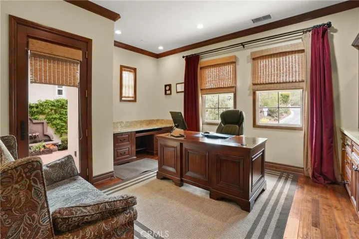 Dedicated office offering custom built-in cabinetry, generous workspace, and seamless access to the gated courtyard.