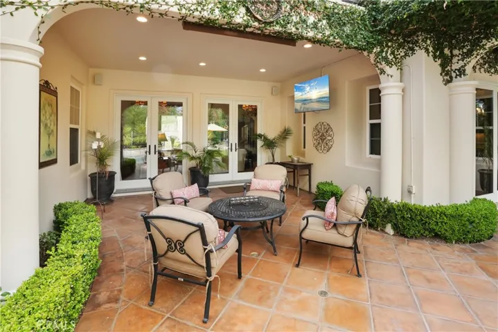 Covered outdoor living area designed for year-round enjoyment, featuring a built-in TV and comfortable seating.