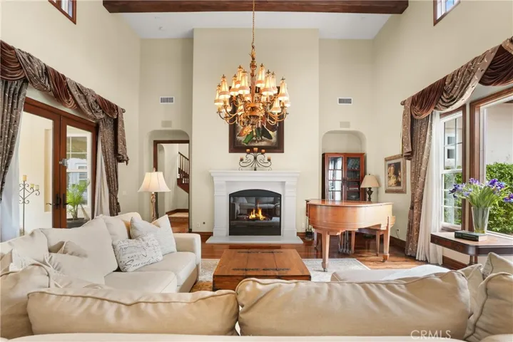 Dramatic great room with soaring ceilings, exposed wood beams, rich hardwood flooring, and elegant architectural details.