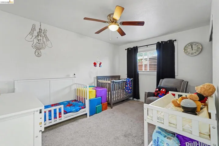 Carpeted room featuring a ceiling fan with integrated lighting, white walls, and a window with horizontal blinds and dark drapery