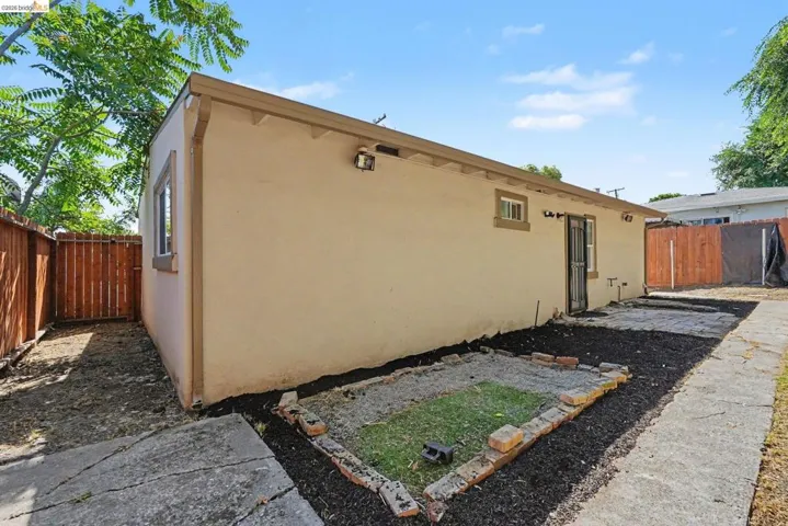 Rear exterior featuring a stucco finish, two windows with trim, and a security screen door