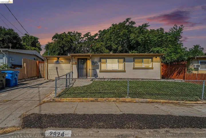 Exterior featuring a stucco finish, attached garage, chain-link front fencing, and a front entry security door