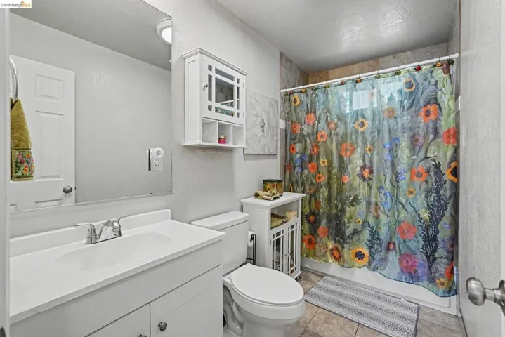 Bathroom featuring a single vanity with a white solid surface countertop and integrated sink, chrome-finish faucet, and a wall-mounted medicine cabinet
