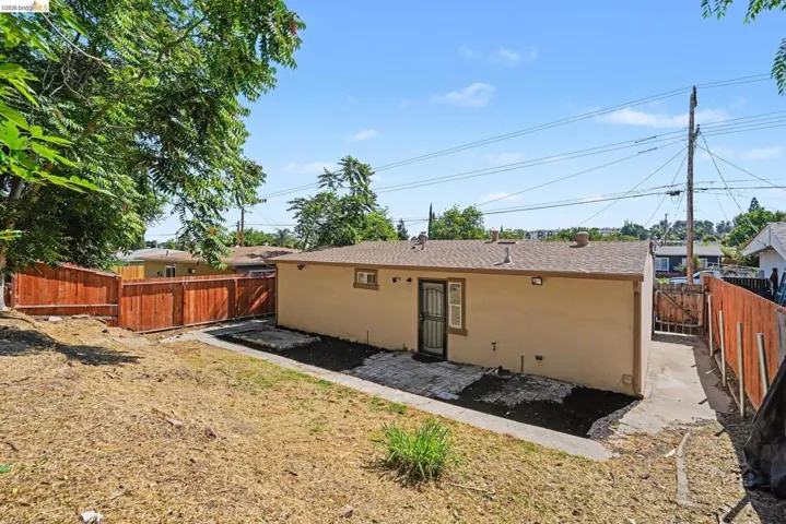 Rear exterior of the property featuring a tan stucco finish and a brown shingle roof