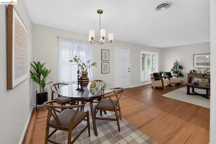 Bright dining area featuring wood-finish flooring, a contemporary chandelier, and a large window with sheer drapery