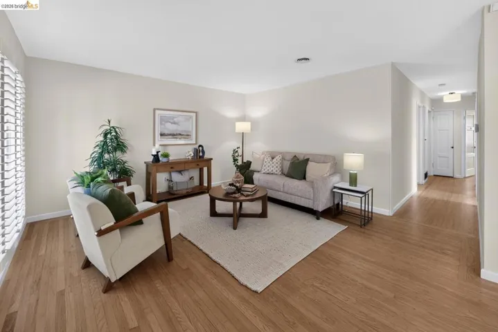 Living area featuring wood-finish flooring, plantation shutters, recessed lighting, and a neutral wall palette