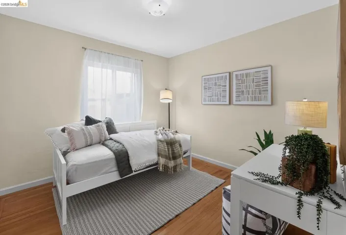 Bedroom featuring wood-finish flooring, a window with sheer curtains, neutral wall paint, and a white ceiling