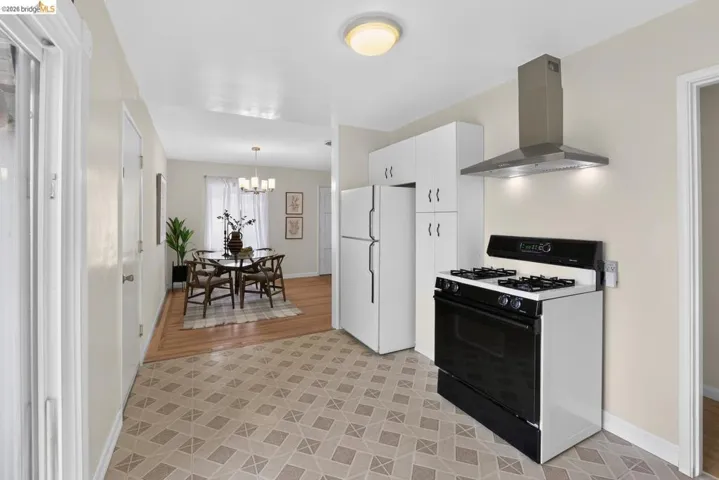 Kitchen featuring patterned tile flooring, white cabinetry, and a stainless steel range hood