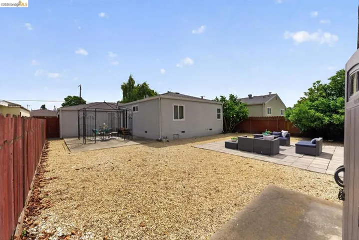 Spacious backyard featuring extensive gravel landscaping, a concrete patio area, and a secondary concrete pad with a metal gazebo structure